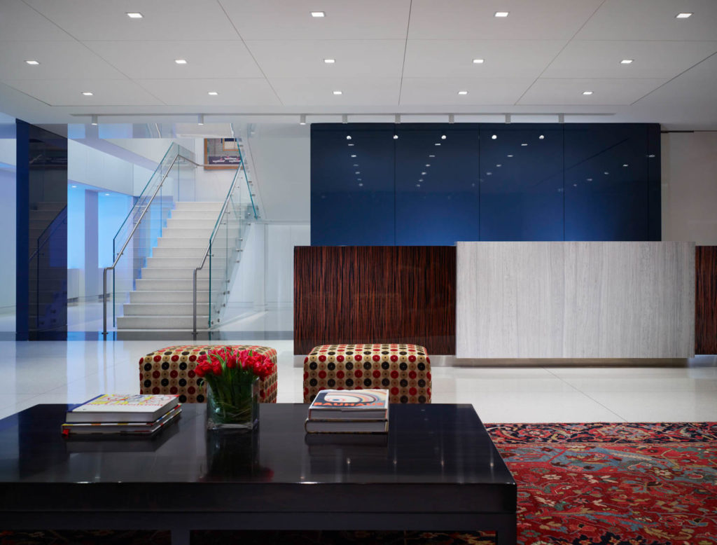 Ropes & Gray by Gensler, reception with patterned ottomans, red tulips and a glass stair, Boston