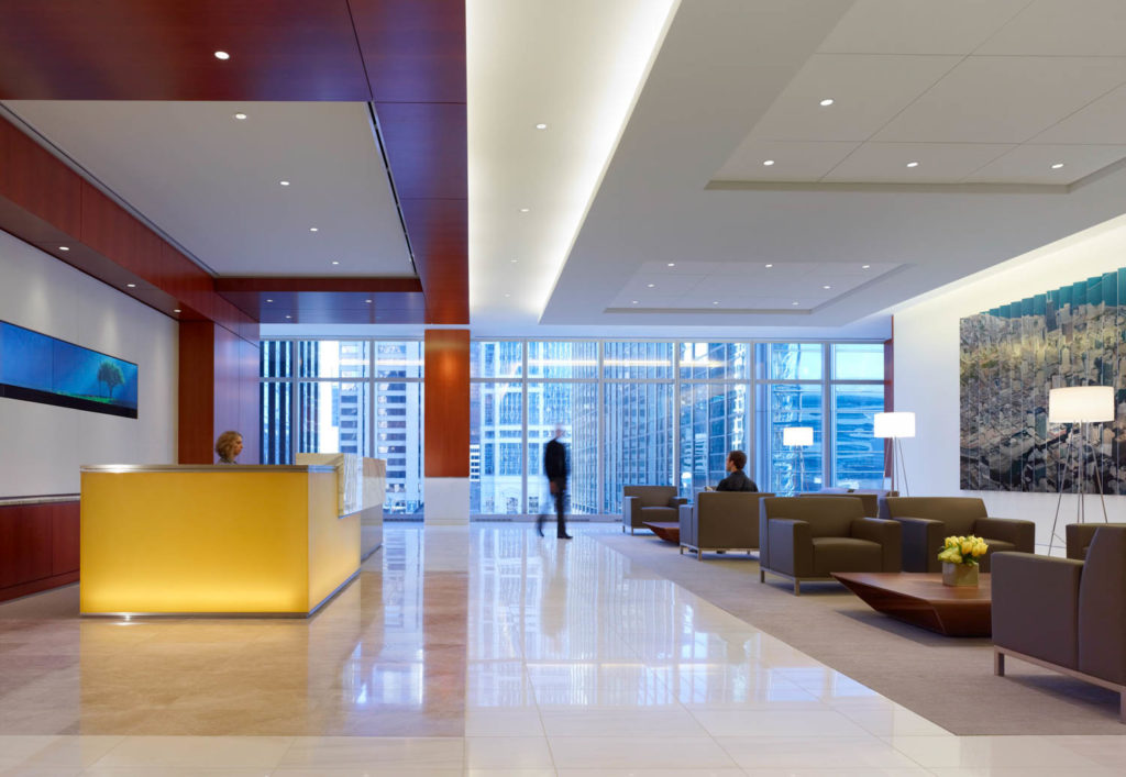 Mesirow Financial by IA Interior Architects, reception with a glowing yellow desk and lounge seating, Chicago