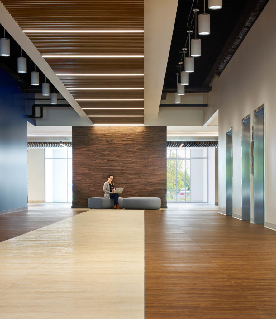 Abbott by Unispace, elevator lobby with stone and wood floors and a stone wall