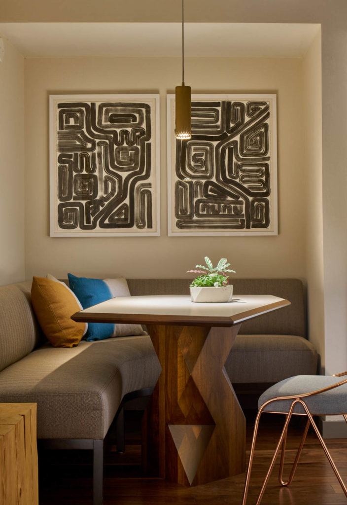 The James Hotel by Dufner Heighes, banquette nook with a wood table beneath framed graphic artwork, Chicago