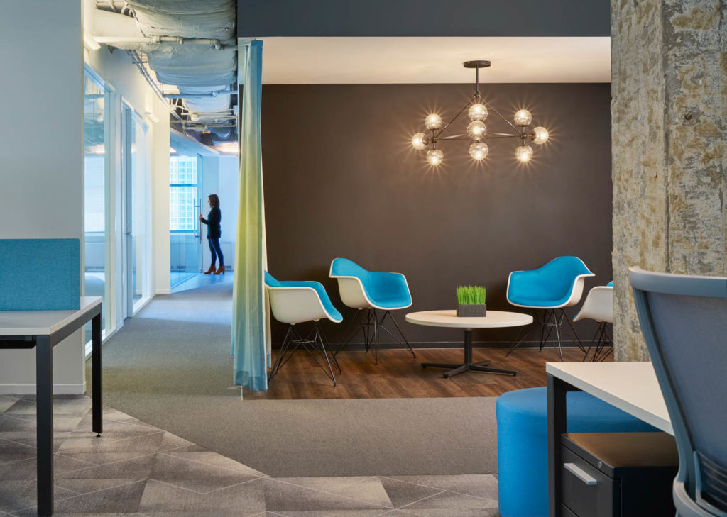 TruQua by Unispace, lounge with blue shell chairs beneath a starburst pendant, Chicago