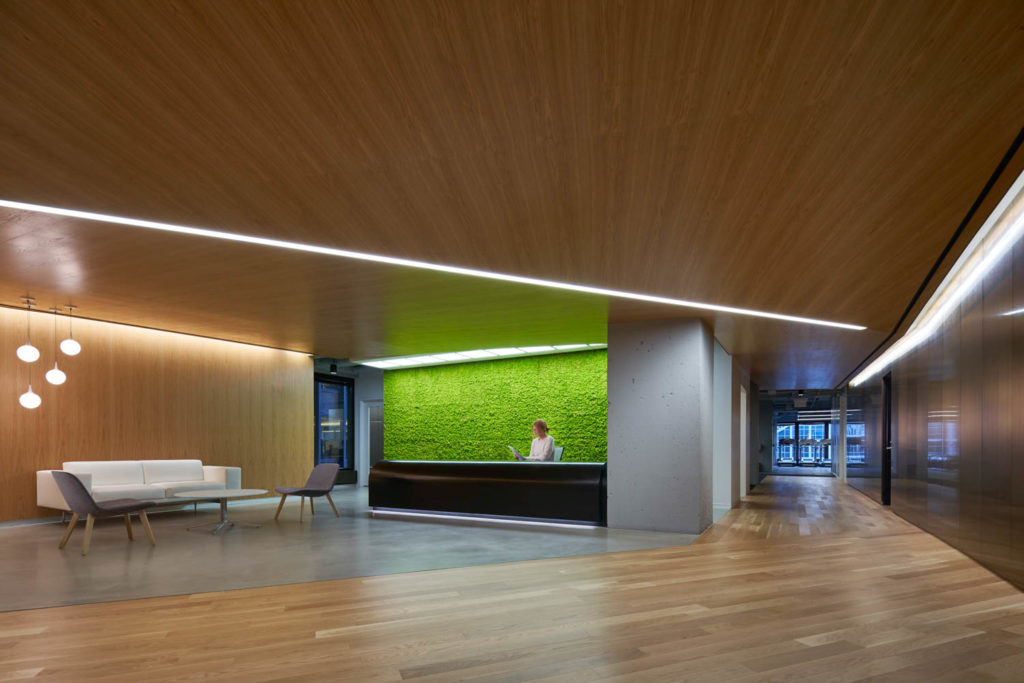 Amenity space by CannonDesign, lounge with a wood ceiling and a green moss wall behind the reception desk, Chicago