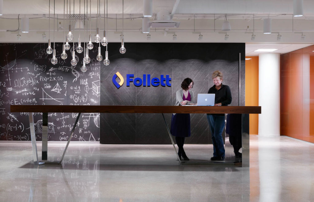 Follett by CannonDesign, reception with a chalkboard wall and suspended light bulbs