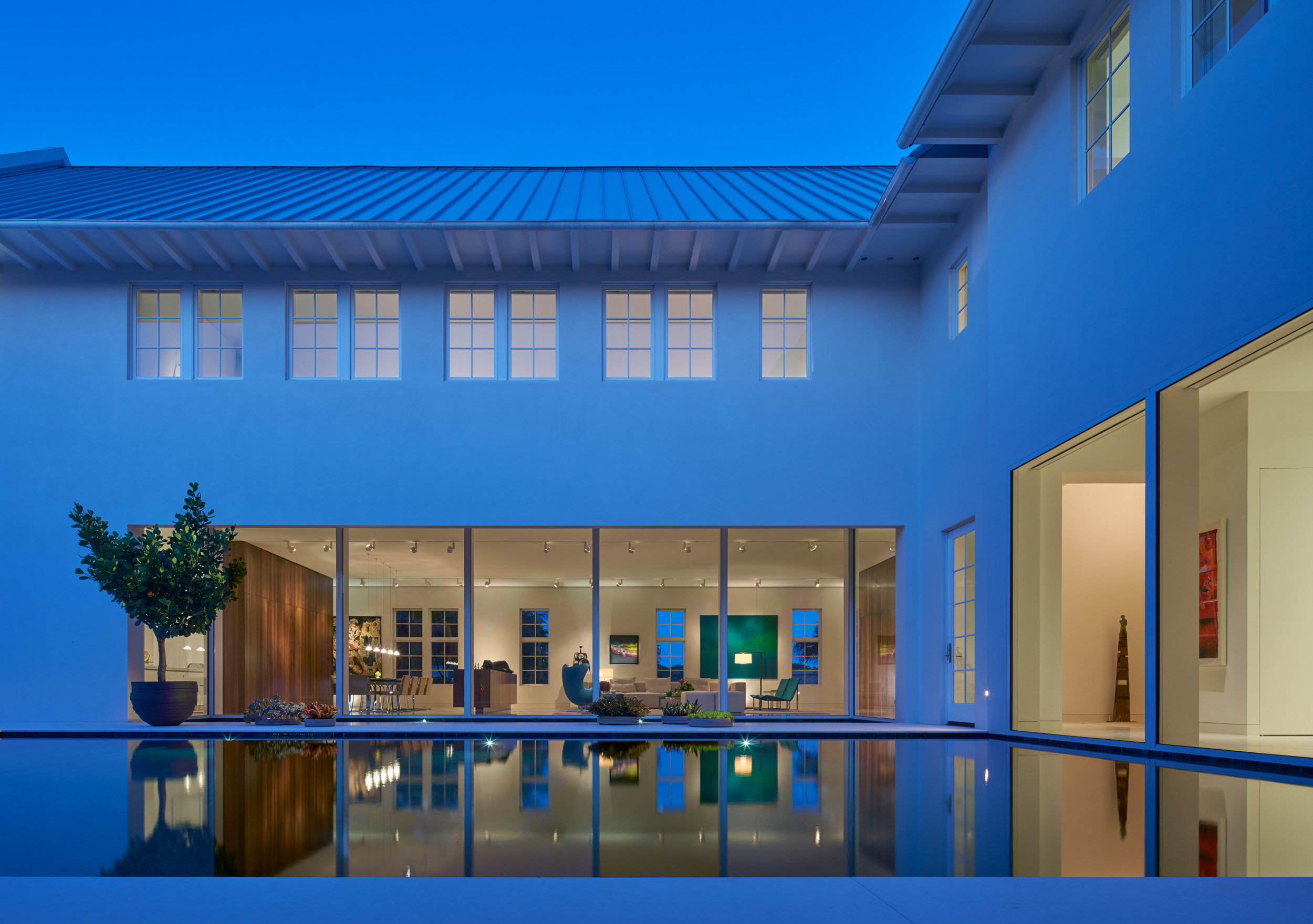 Podesta Residence by ParkFowler Plus at dusk, glass-walled living spaces reflected in the courtyard pool, Vero Beach, Florida