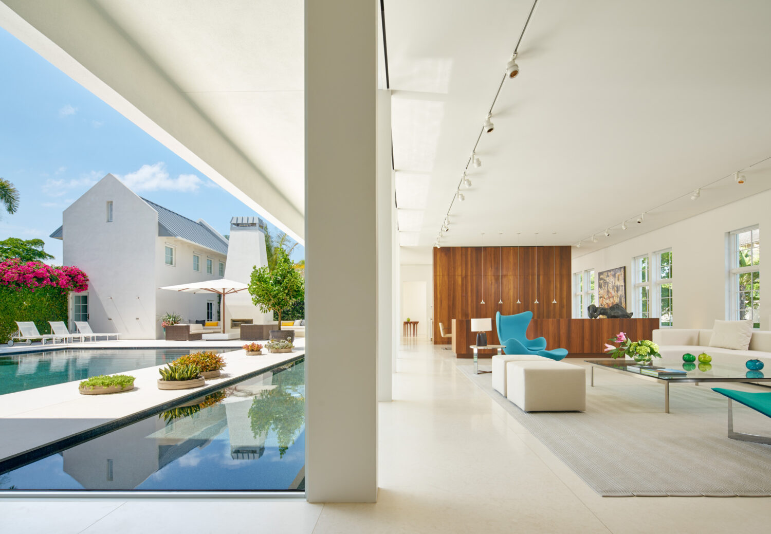 Living room opening onto the pool courtyard, with walnut paneling and a turquoise Egg chair