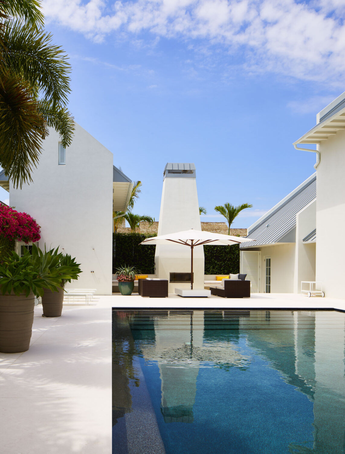 Pool courtyard with the outdoor fireplace, umbrella and gabled wings of the Podesta Residence