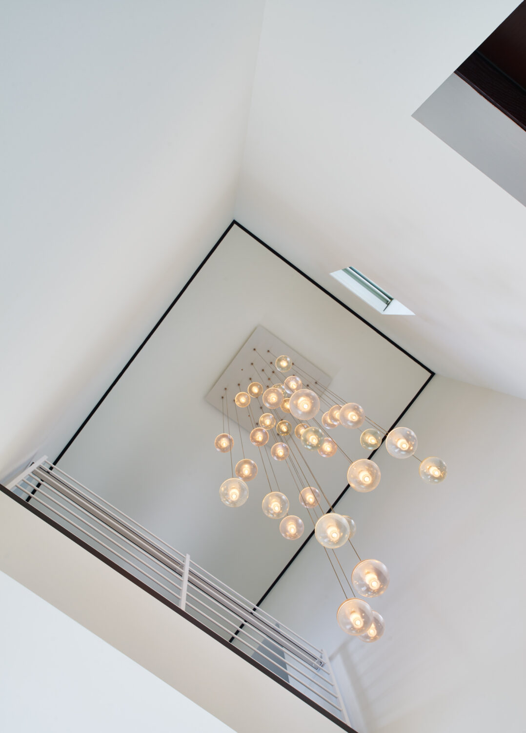 Looking up a stair hall to a cluster of glass globe pendants