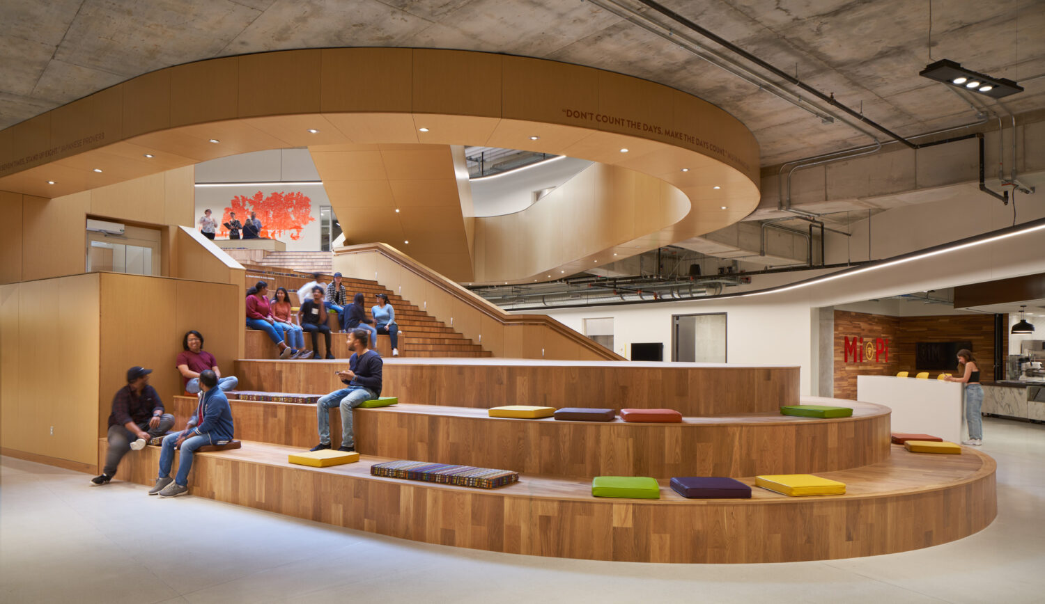 Students sitting on the terraced cedar Gathering Stair with colorful cushions at the Western Michigan University Student Center