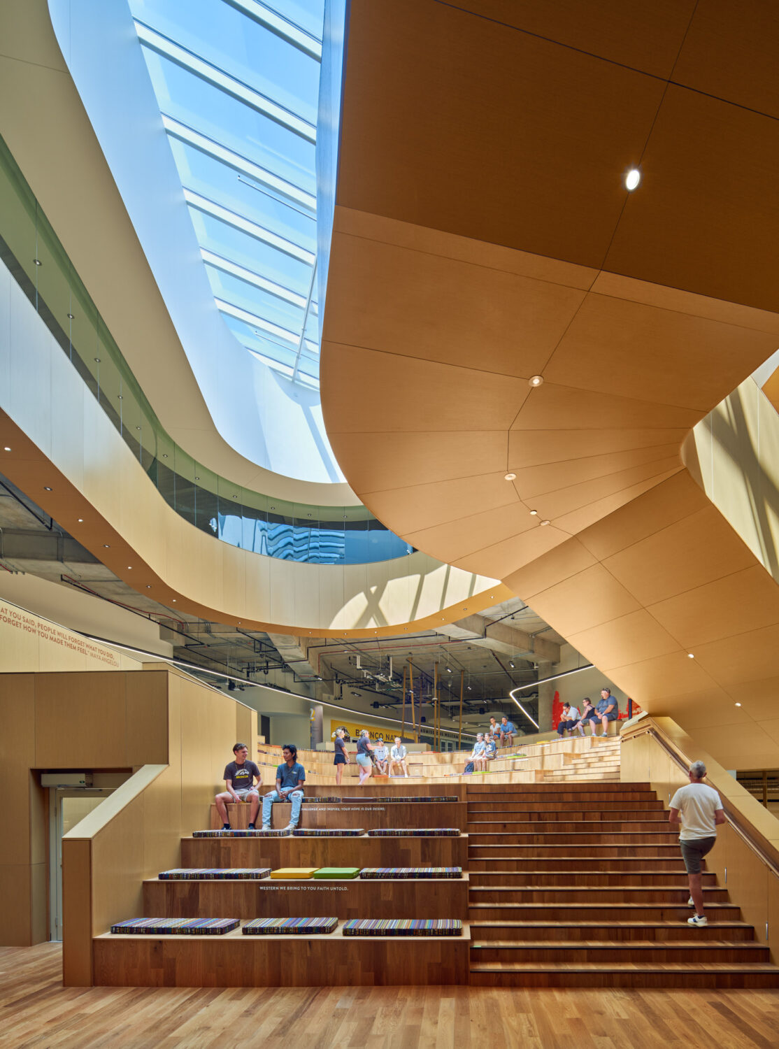 Looking up the Gathering Stair at the Western Michigan University Student Center toward curved cedar soffits and a long skylight
