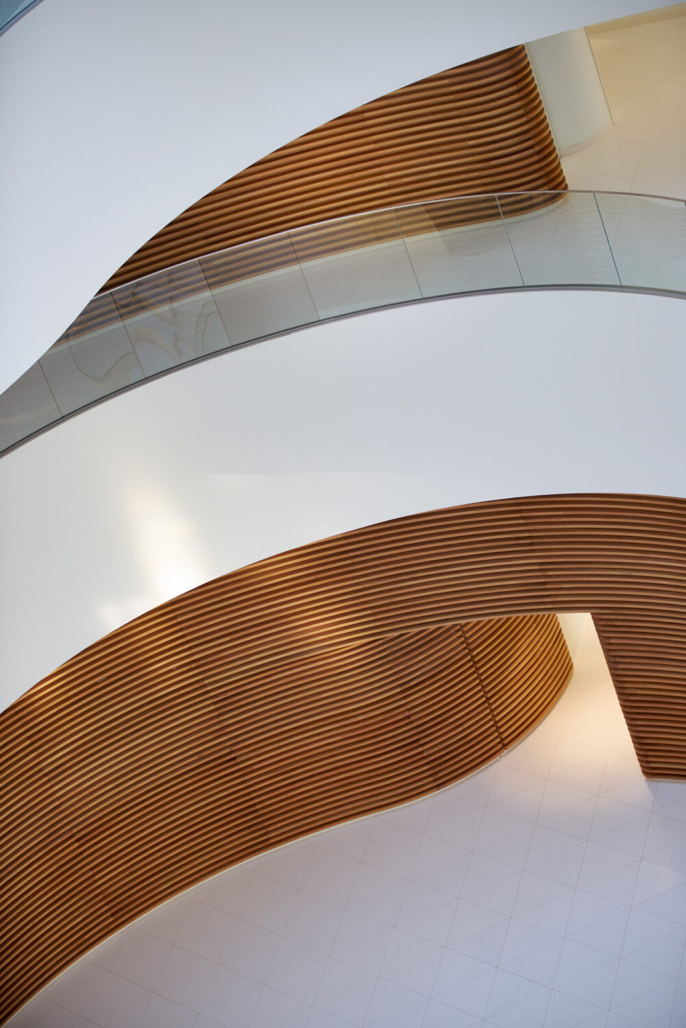 Curved wood slat walls and a glass railing in the CJ Blossom Park atrium, seen from above