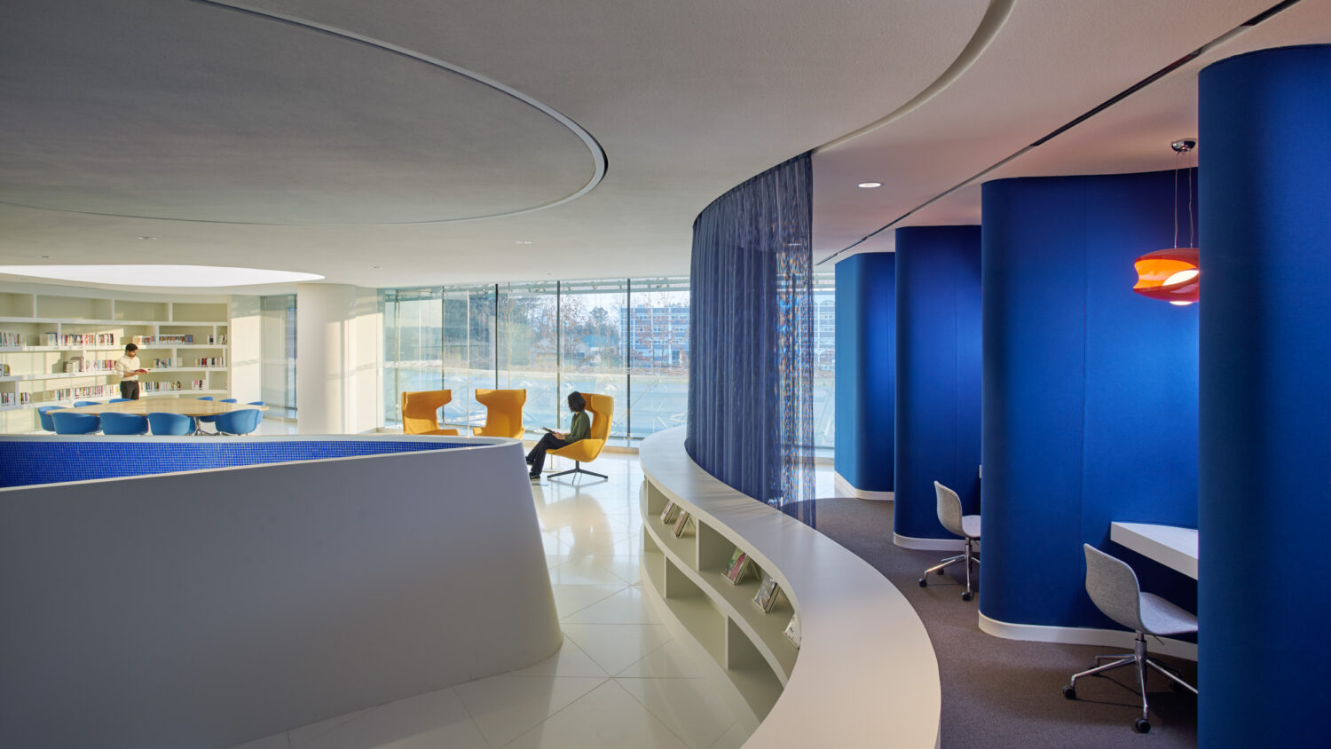 Library and study area at CJ Blossom Park with yellow lounge chairs and blue fabric-wrapped study carrels