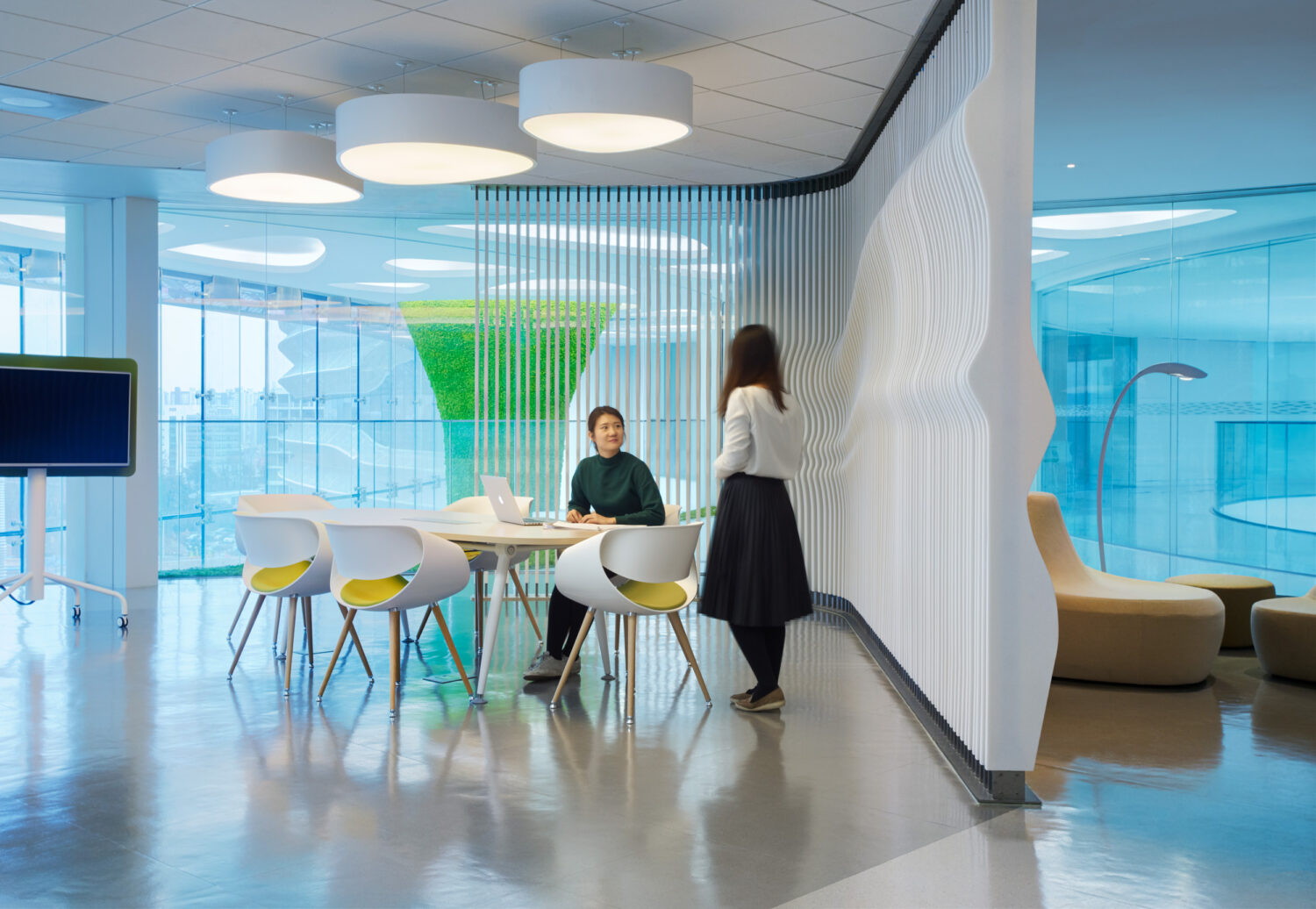 Two researchers at a meeting table beside a sculpted white slat wall at CJ Blossom Park, with the moss column visible beyond