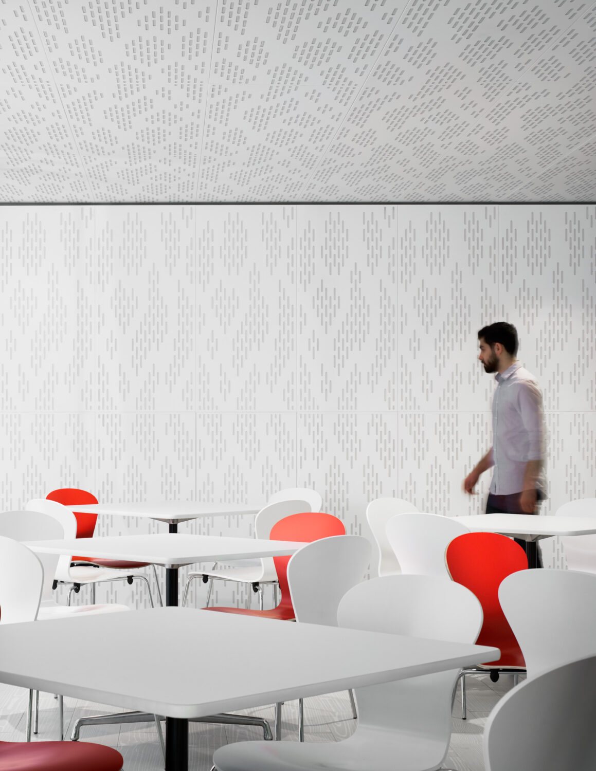 Café at ABC DC by SmithGroup, white tables and red chairs against a textured white wall