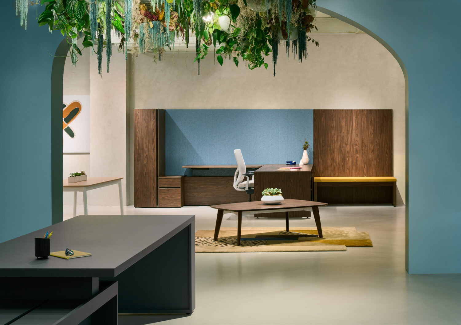 Blue arched alcove with a wood desk and hanging greenery in the Three H showroom