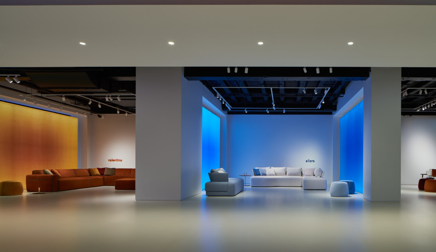 Blue lit alcove with a low white sofa at the end of a gallery in the Bernhardt showroom