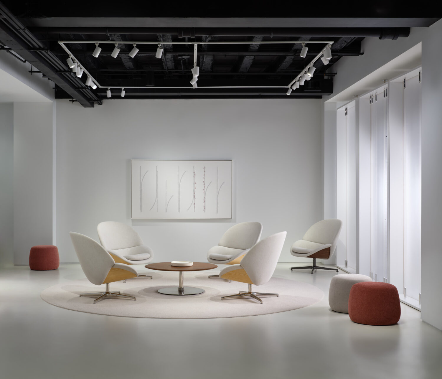 White lounge chairs gathered on a round rug in a bright white Bernhardt showroom
