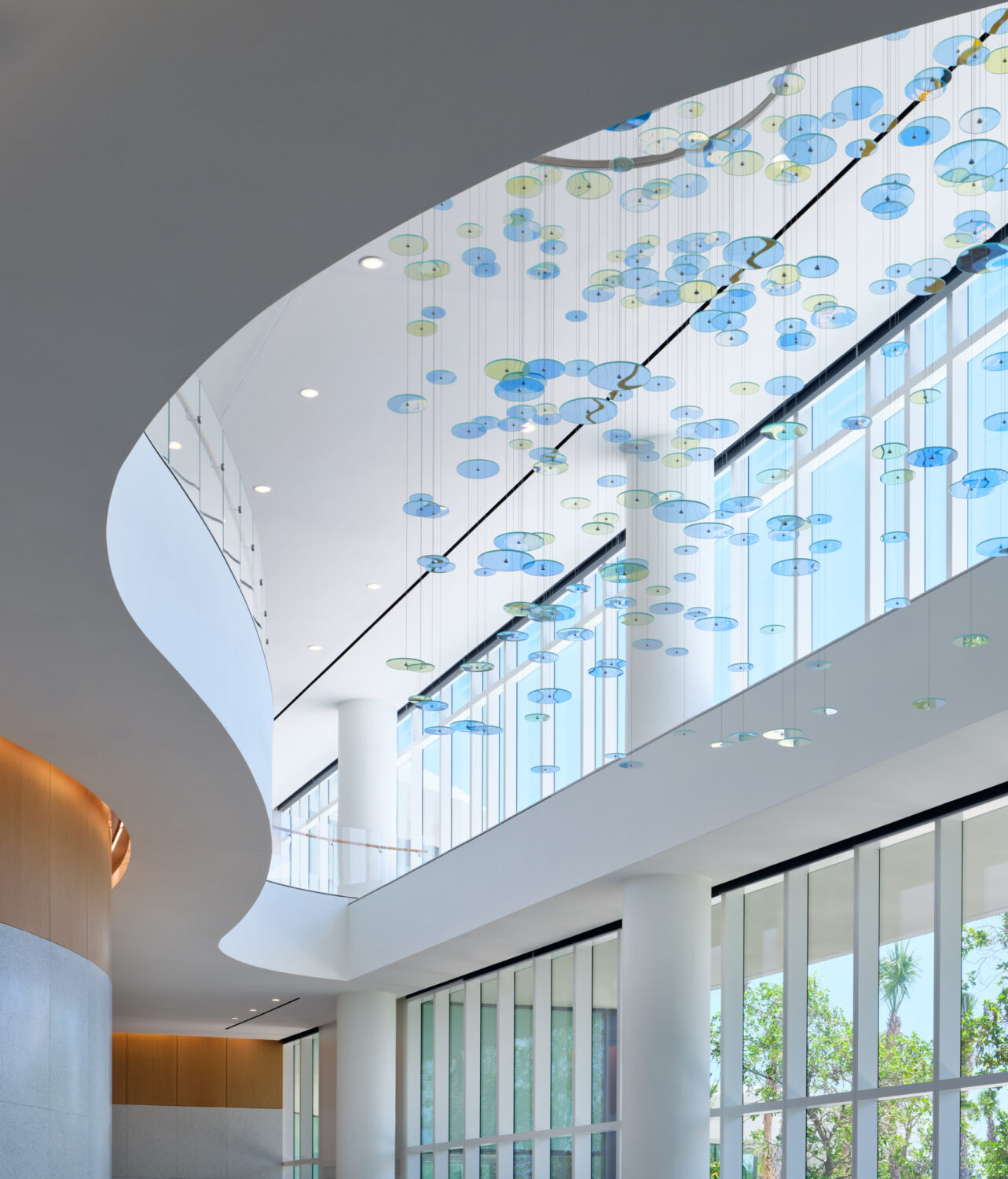 Skylit atrium with suspended glass discs and a sweeping curved ceiling, Braman Comprehensive Cancer Center by CannonDesign, Miami Beach, Florida