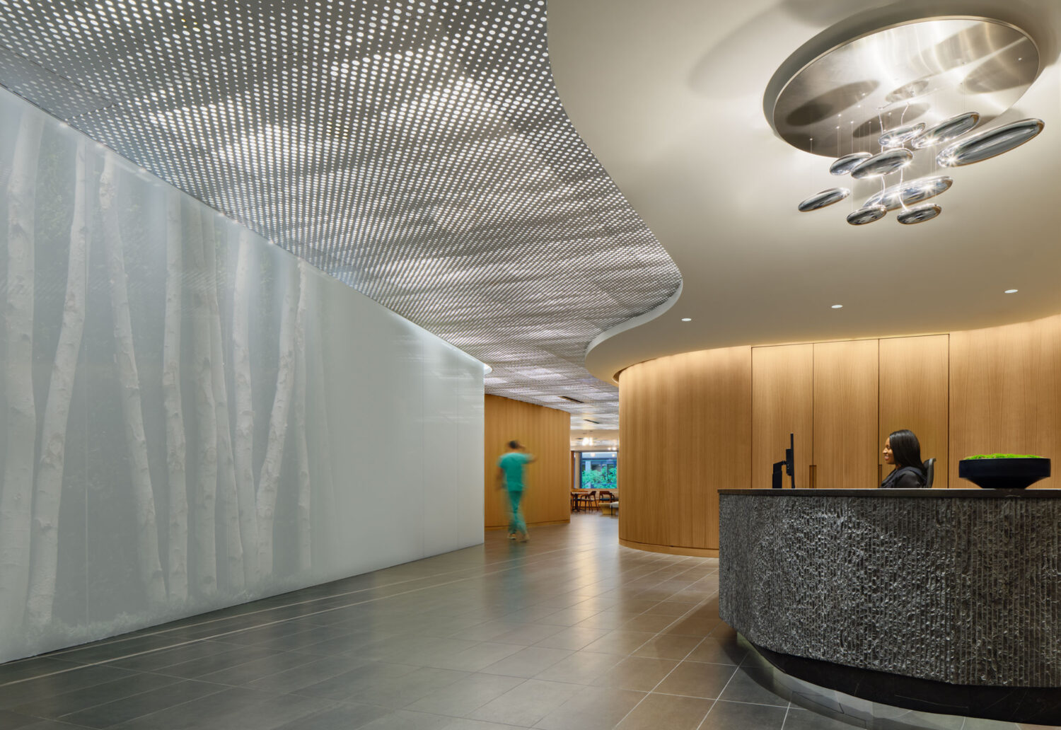 Stone reception desk beneath a backlit perforated ceiling and a cluster of mirrored spheres at the Northwestern Medicine Faculty Office Center