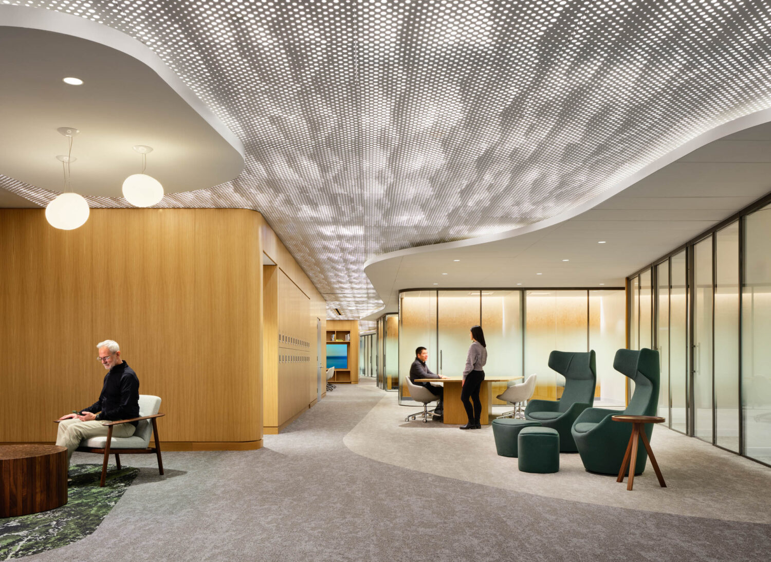 Physicians reading in high-backed lounge chairs on a moss-patterned rug under a dappled perforated ceiling at the Northwestern Medicine Faculty Office Center
