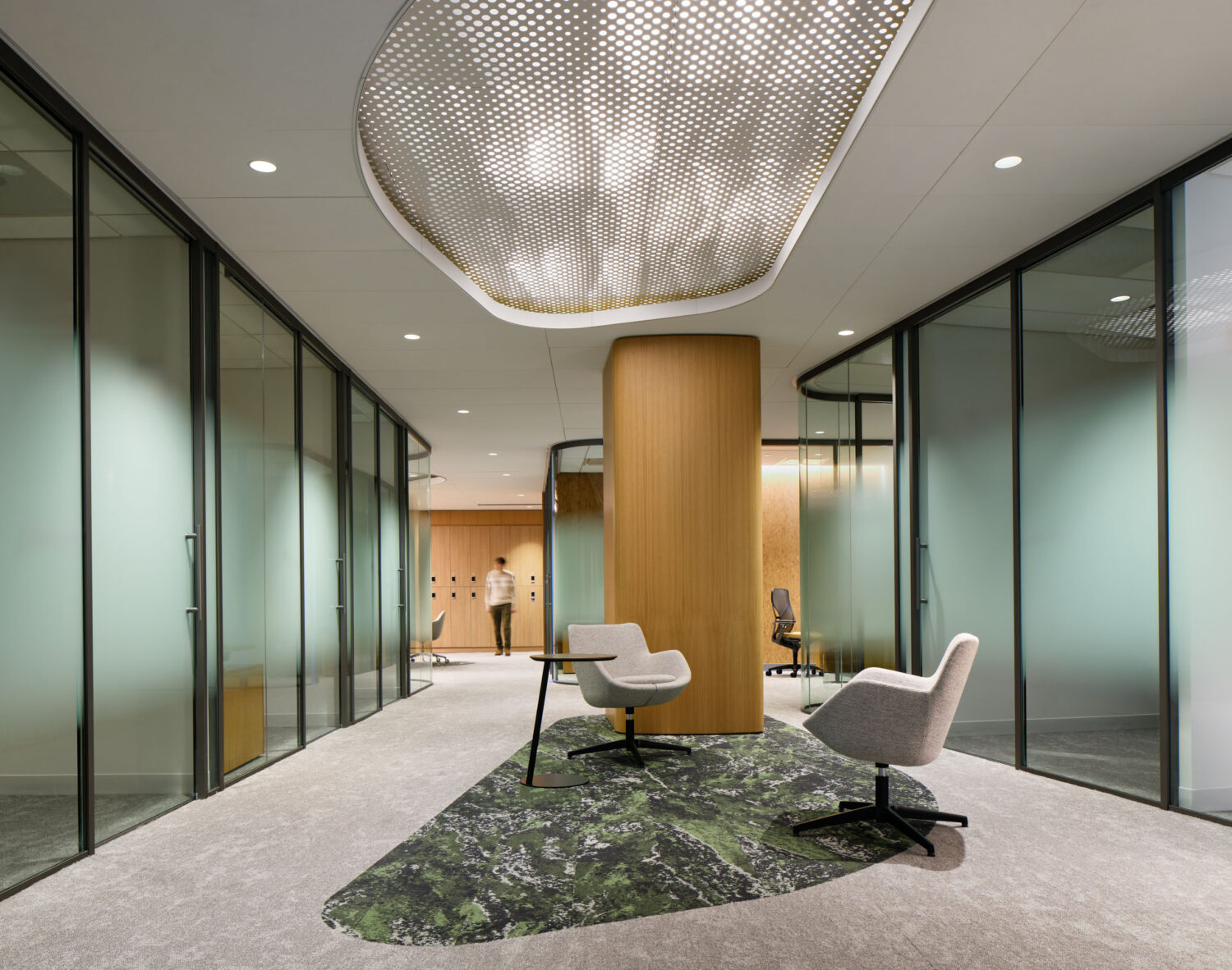 Lounge chairs on a green moss rug between rows of frosted glass offices at the Northwestern Medicine Faculty Office Center