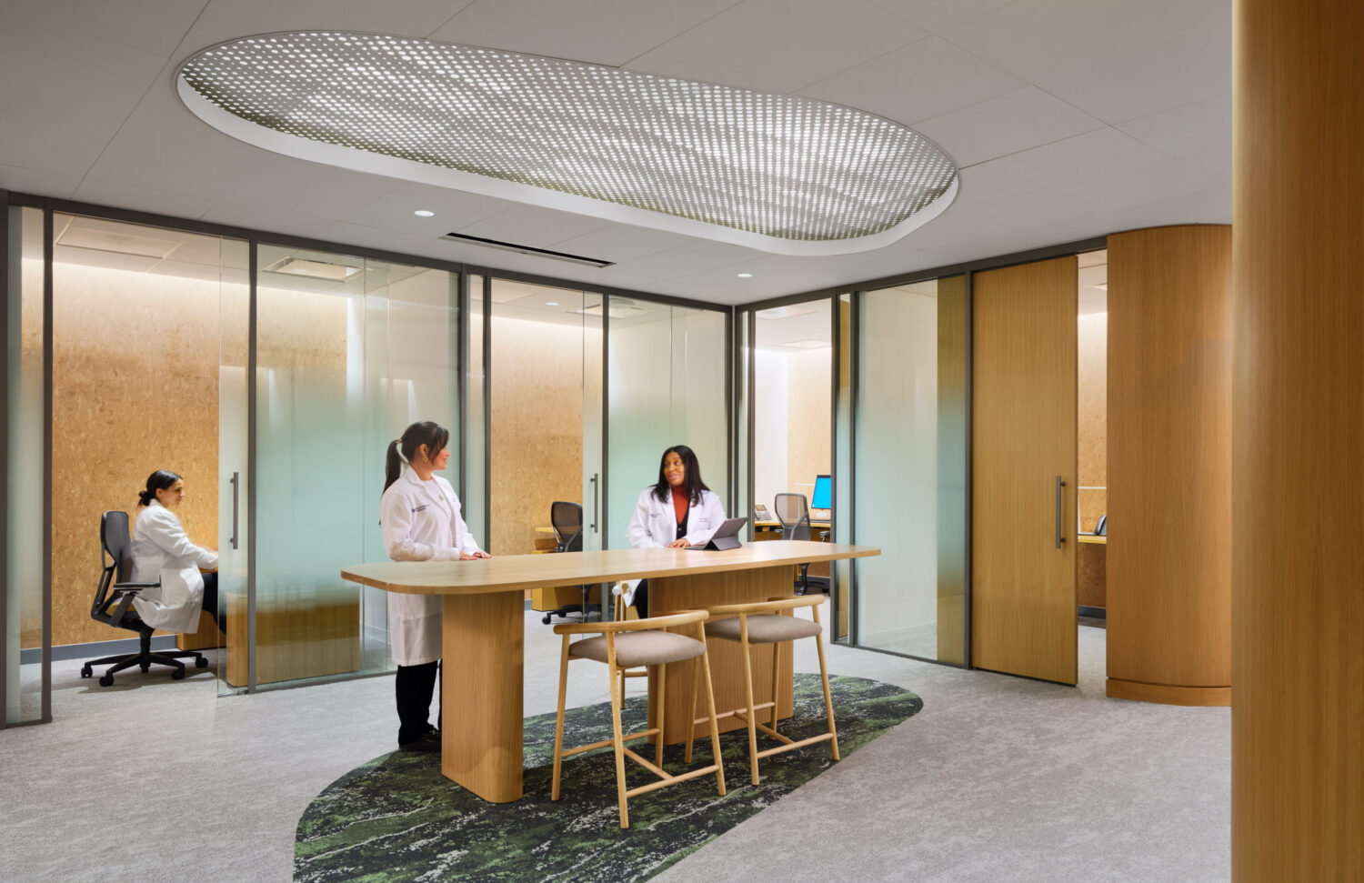 Physicians at an oak standing table and a desk in front of frosted glass offices at the Northwestern Medicine Faculty Office Center