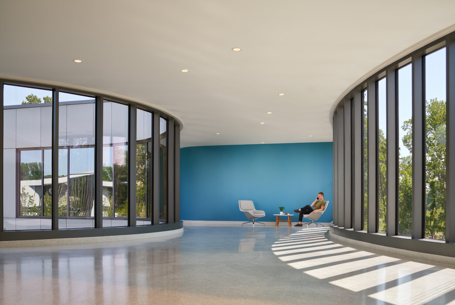 Curved window lounge with a blue accent wall and sunlight on the terrazzo, Sheppard Pratt Baltimore/Washington Campus by CannonDesign, Elkridge, Maryland