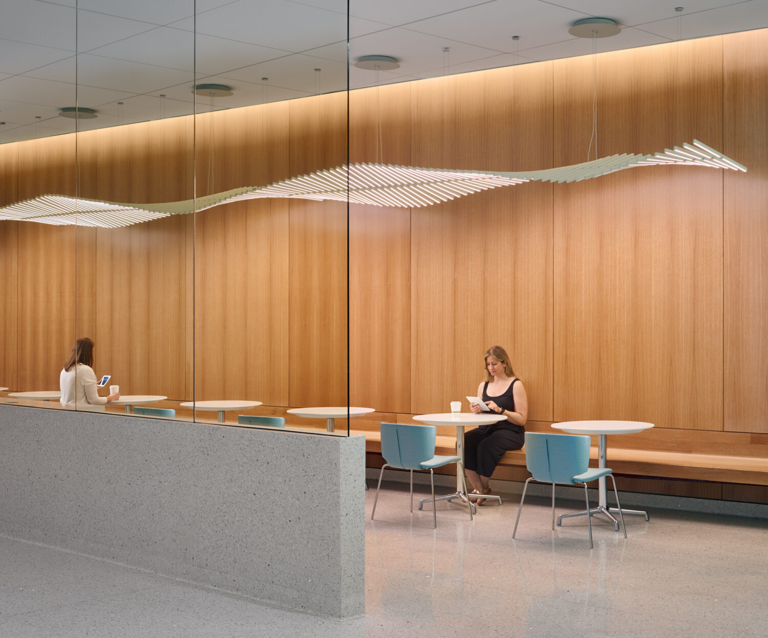 Café with warm wood walls and a wave-shaped light sculpture, Skolnick Surgical Tower by CannonDesign, Miami Beach, Florida