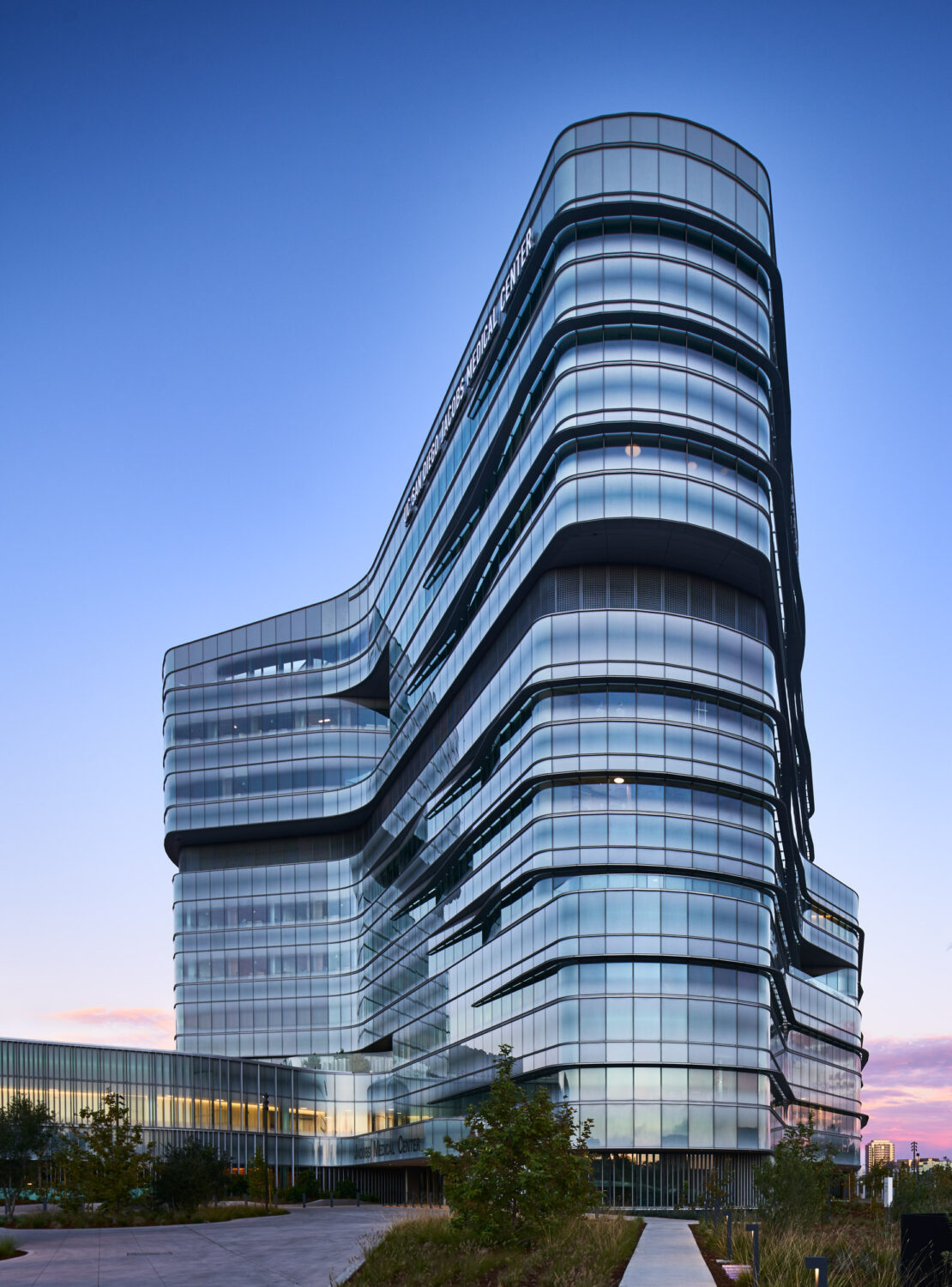Tower at dusk with layered, curving glass bands, Jacobs Medical Center, UC San Diego Health by Yazdani Studio of CannonDesign, La Jolla, California