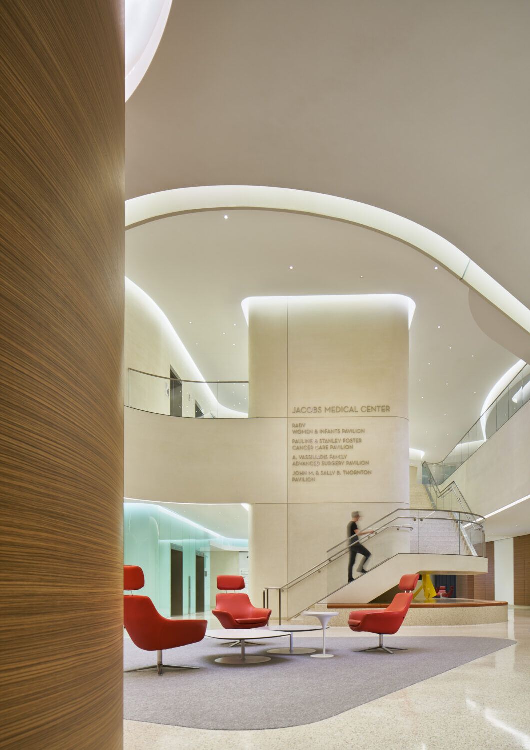 Atrium with red lounge chairs and a curving stair, Jacobs Medical Center, UC San Diego Health by Yazdani Studio of CannonDesign, La Jolla, California