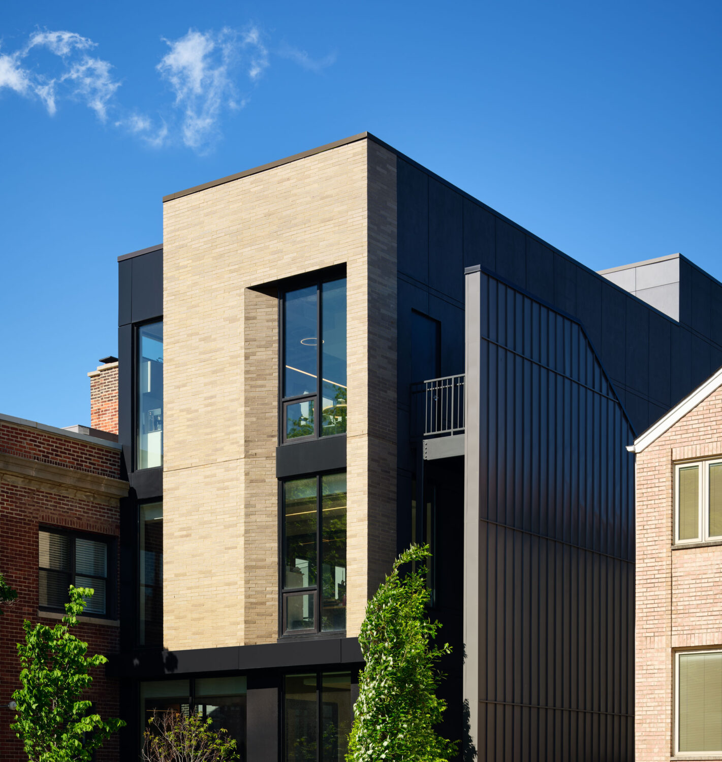 Cream brick volume and dark standing seam metal cladding of Thresholds Center for Mental Wellbeing South against a blue sky