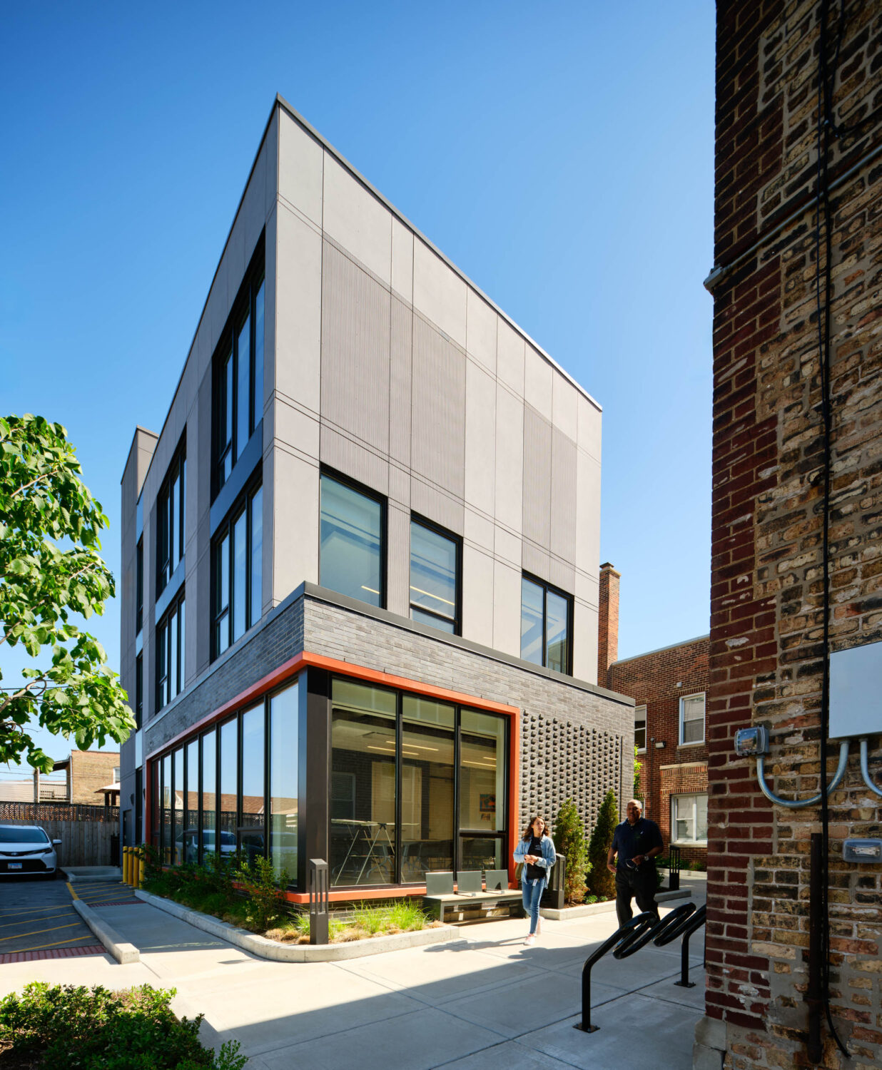 Gray panel addition of Thresholds Center for Mental Wellbeing South with an orange framed glass corner and patterned brick base