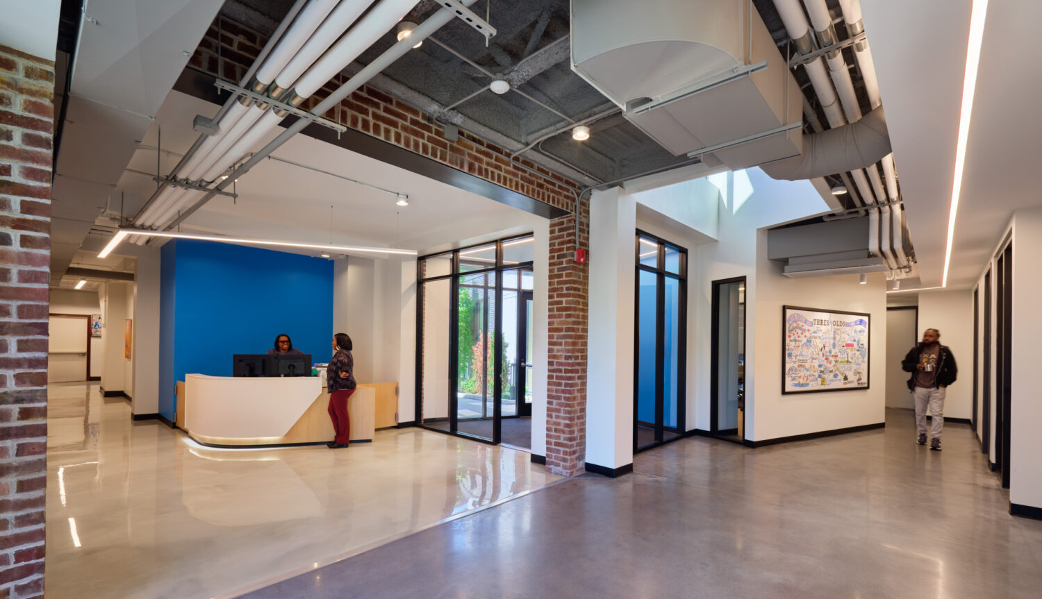 Lobby with blue accent wall, curved reception desk and exposed brick at Thresholds Center for Mental Wellbeing South
