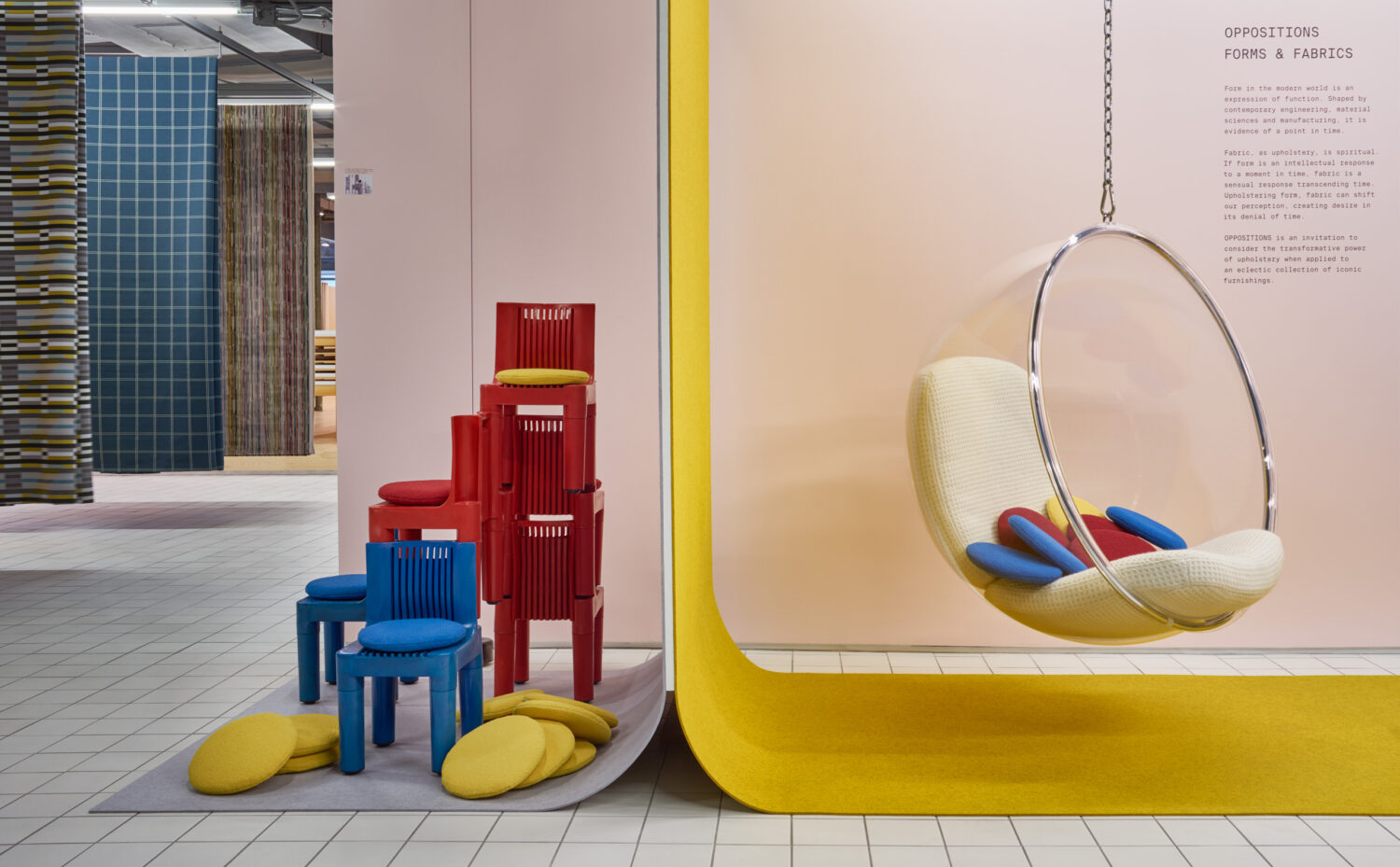Red stacked chairs and a hanging egg chair on a yellow curve in the Designtex showroom