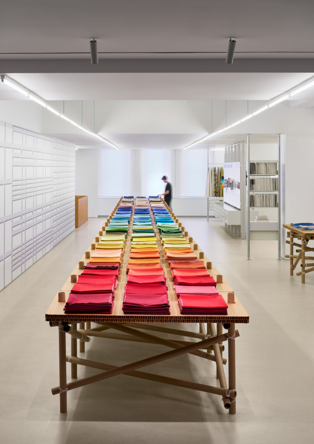 Long table covered in rainbow rows of fabric samples running down a white Designtex showroom