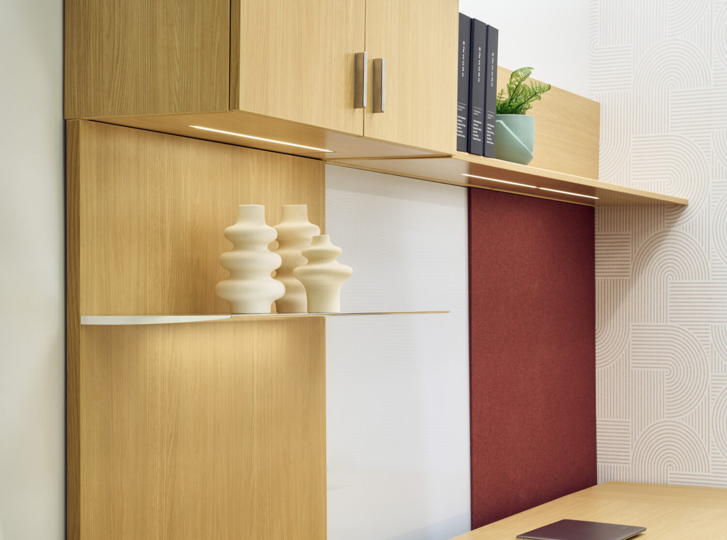 Oak wall cabinets with ceramic vases and a burgundy panel in the Enwork showroom