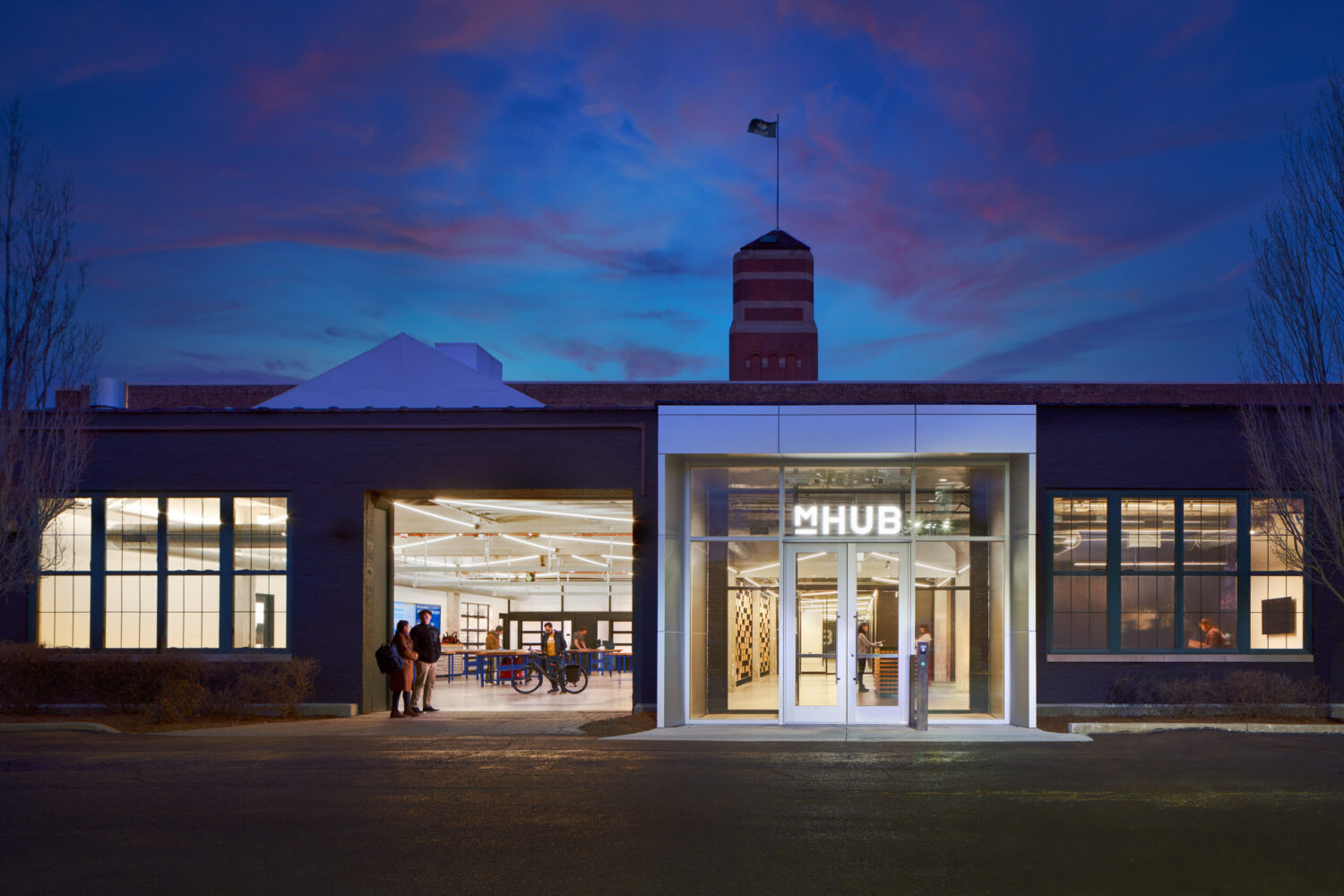 Brick warehouse entrance of mHUB glowing at dusk under a purple sky in Chicago