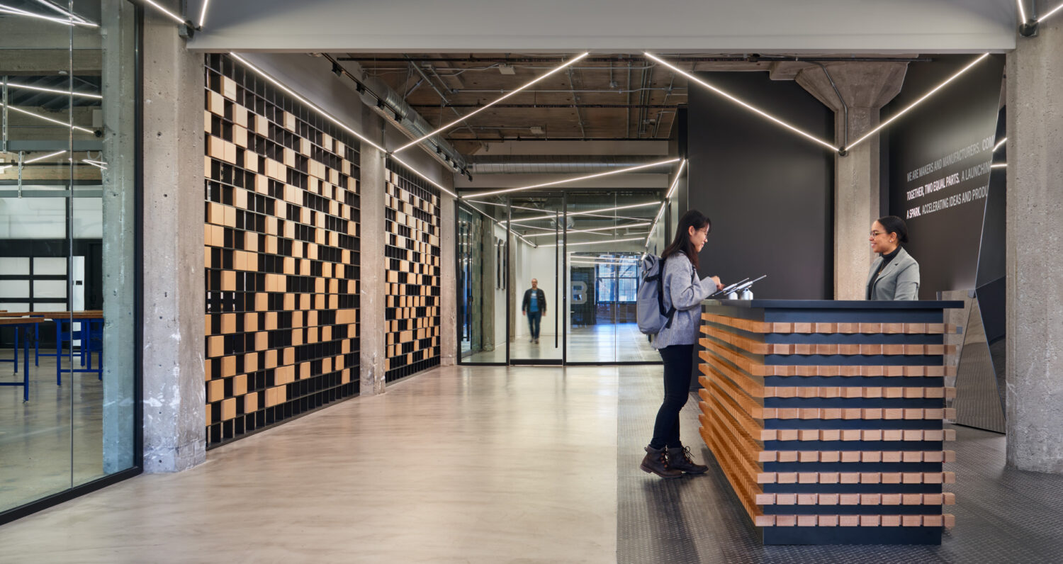 Reception desk with a wood block front and patterned wall panels inside mHUB