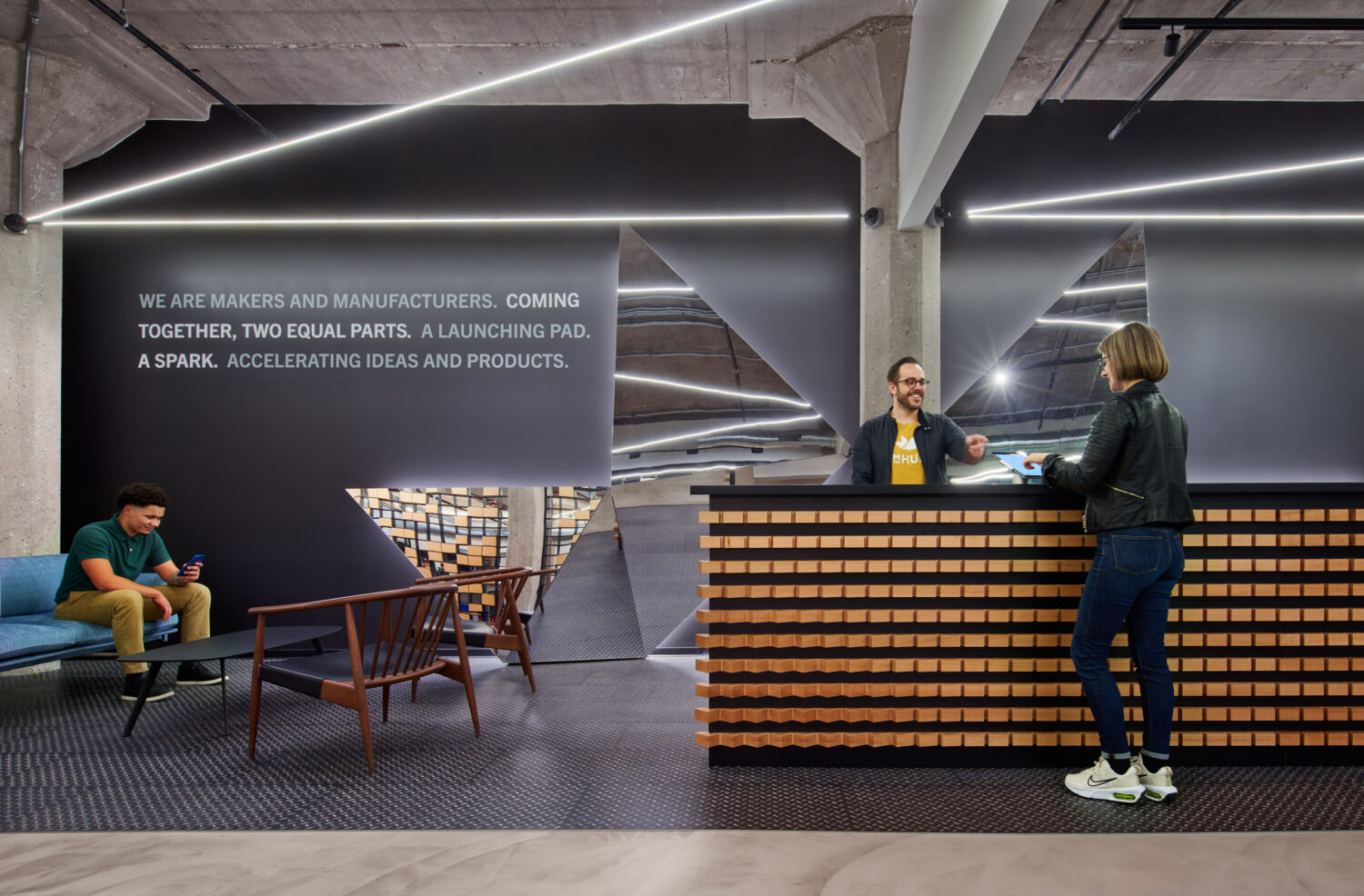 Lobby lounge with angled light lines and a makers statement on the wall at mHUB