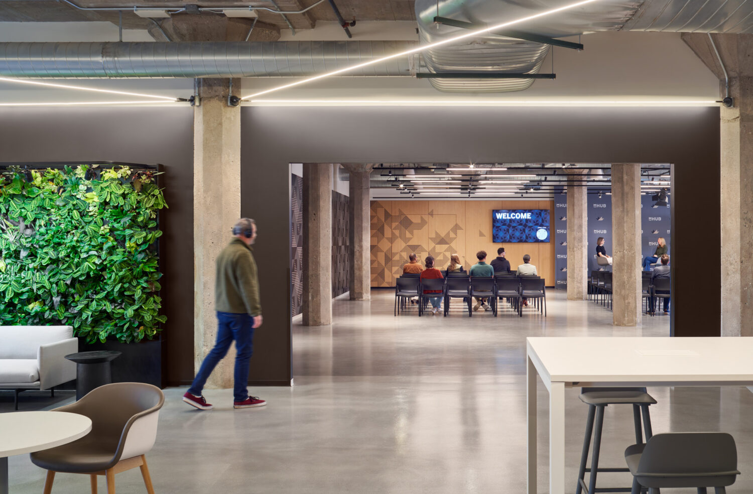 Green living wall beside a corridor leading to an event space at mHUB