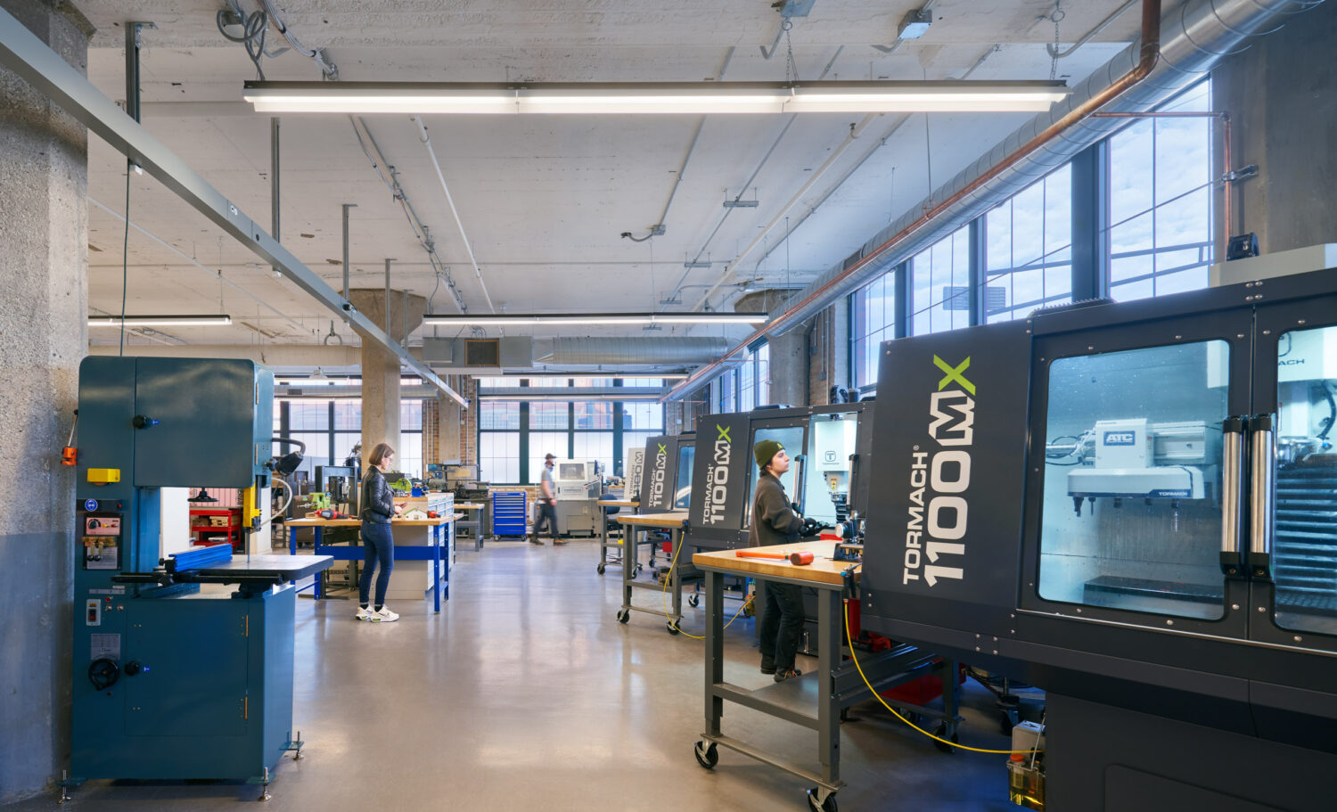 Metals lab with a band saw and CNC machines at mHUB