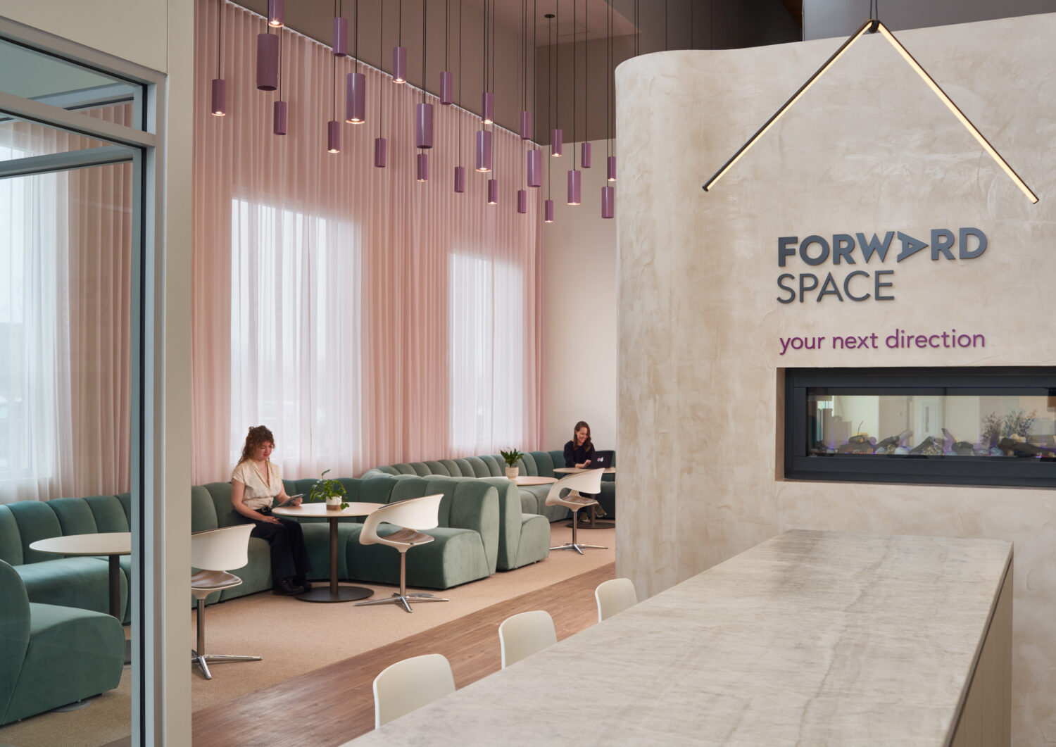 Pink curtains, green booth seating and a fireplace wall with the Forward Space logo