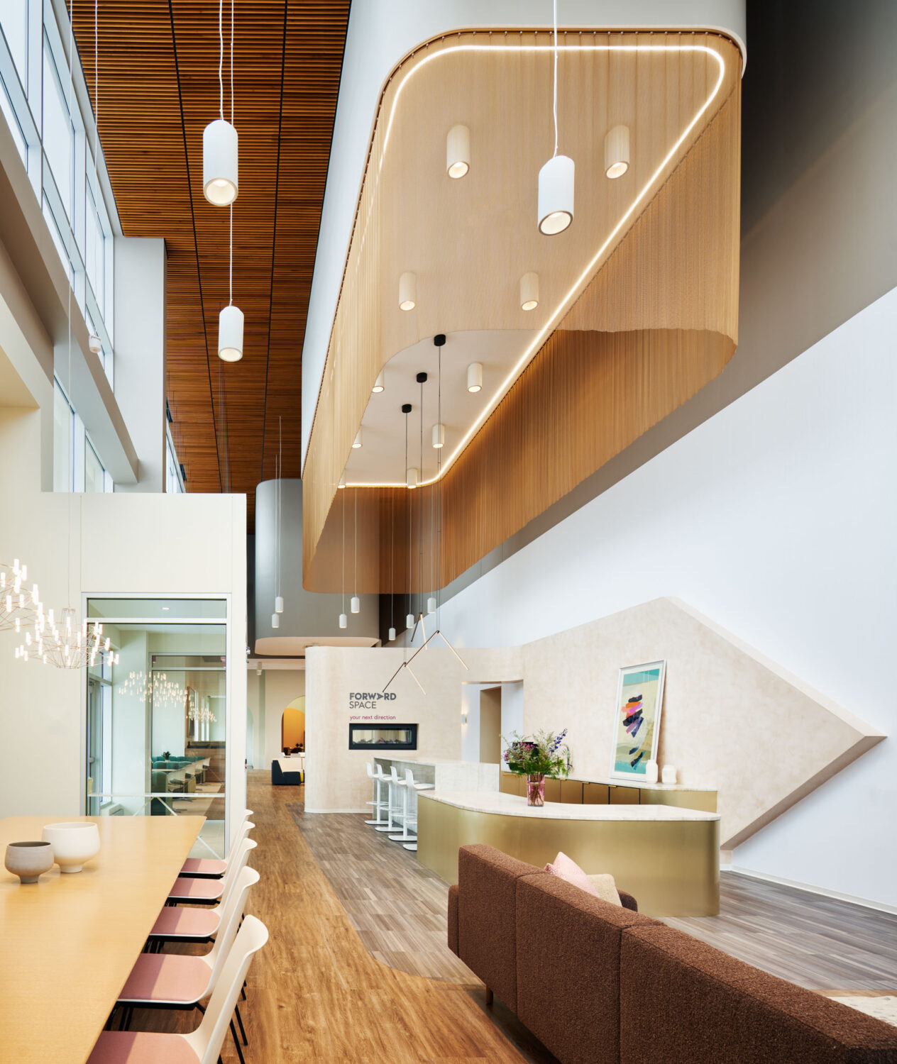 Reception desk under a wood clad ceiling with a glowing suspended light frame at Forward Space
