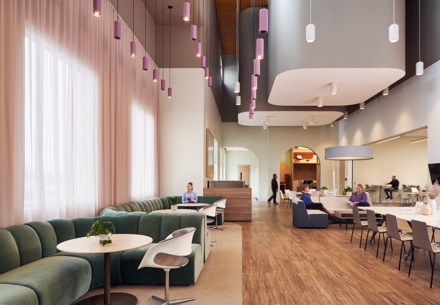 Long cafe with green banquettes, pink curtains and suspended ceiling clouds at Forward Space