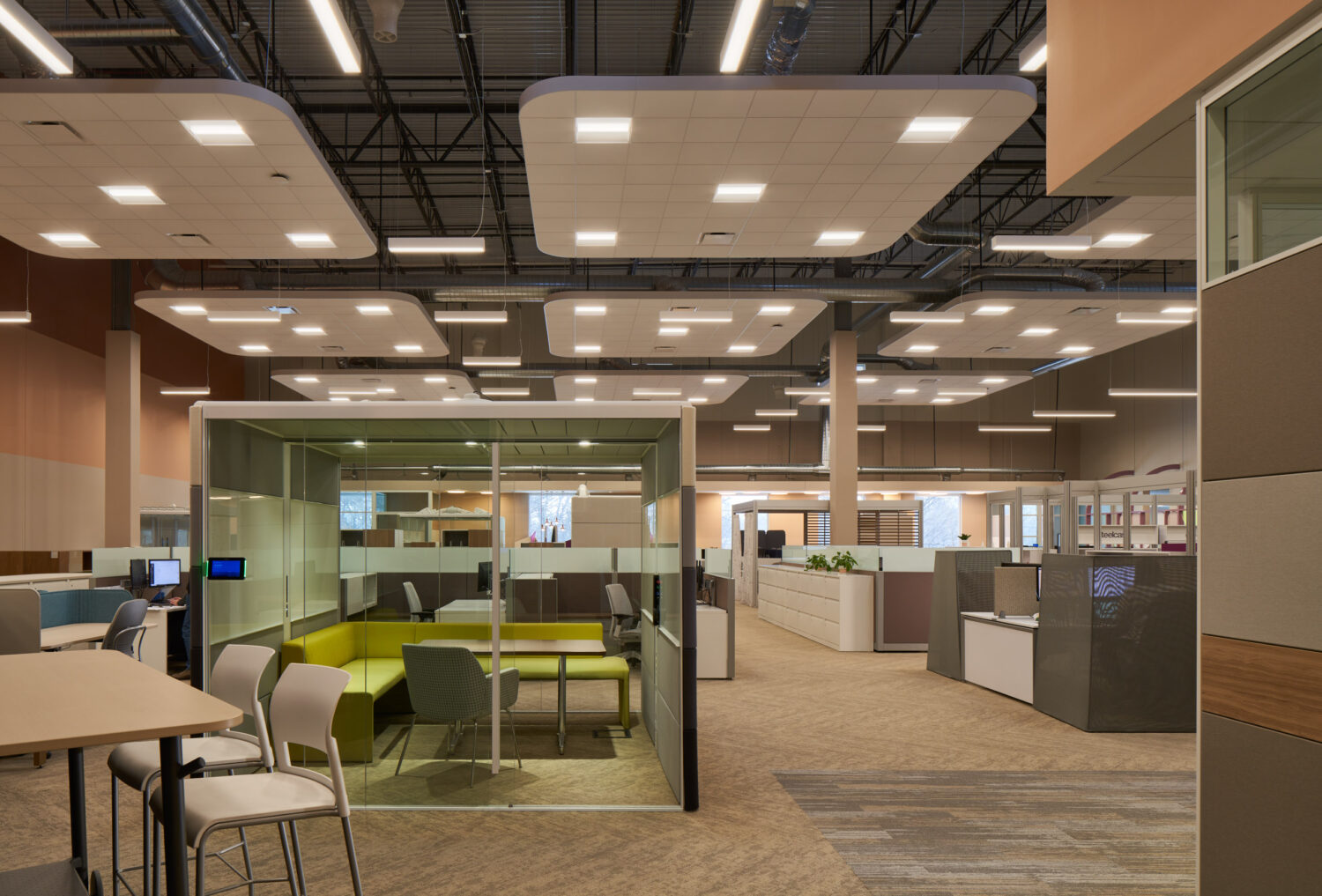 Open office showroom with a glass meeting room and lime lounge seating at Forward Space
