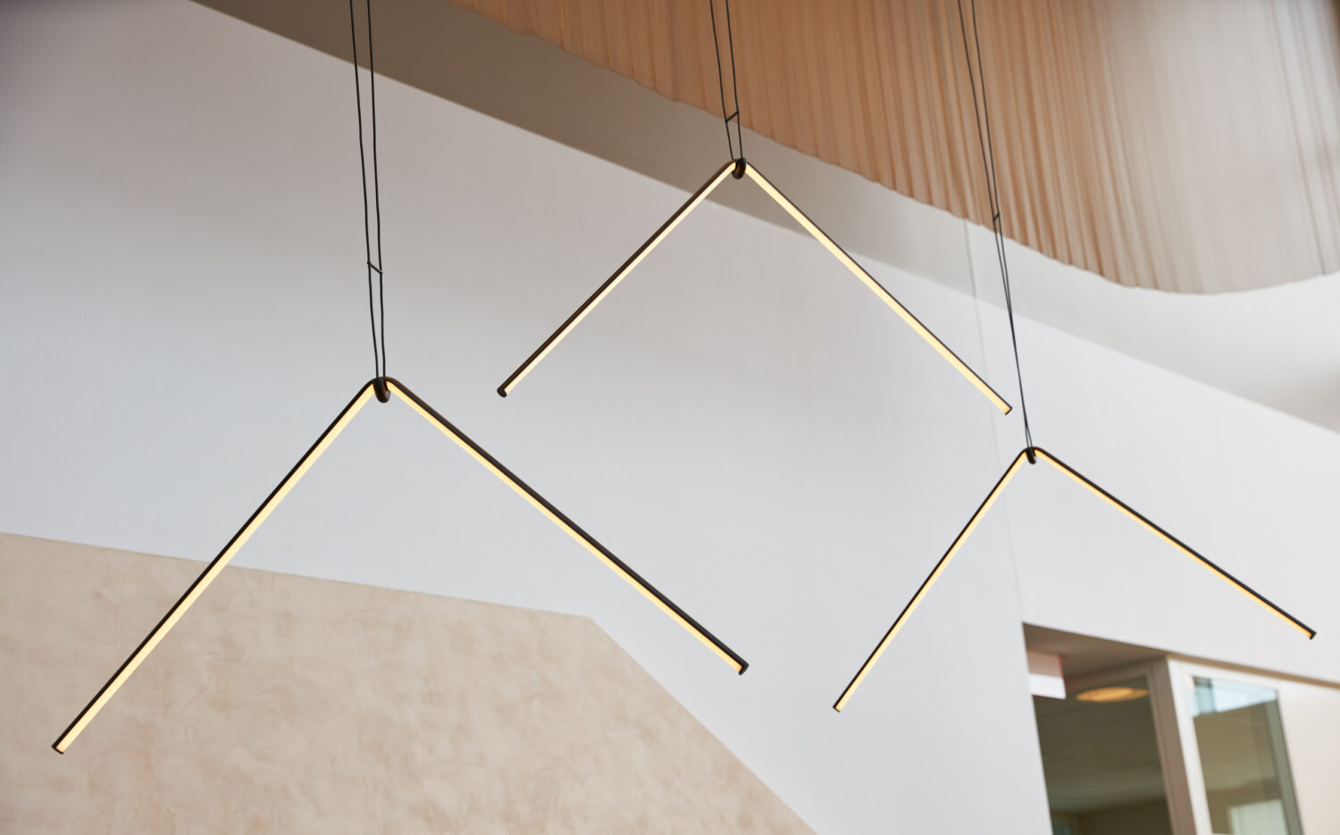 Angled linear pendants floating in the double height space at Forward Space
