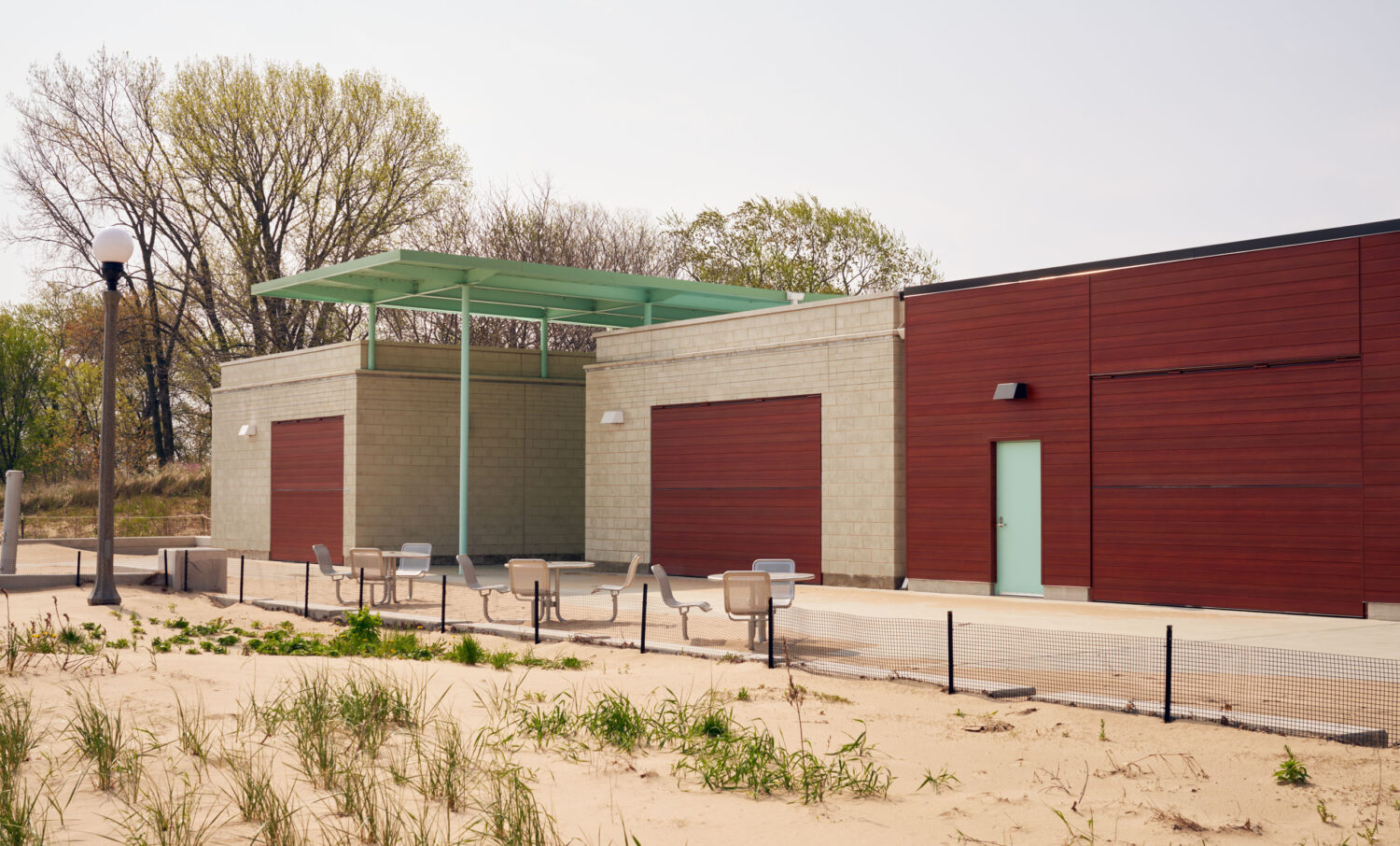 South Shore Beach House in spring with shutters closed, masonry pavilions and green canopy above the sand