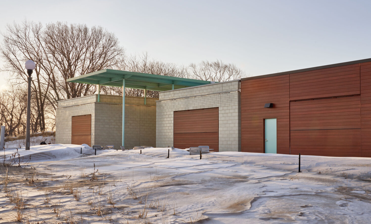 South Shore Beach House in winter, snow drifted across the patio in front of the masonry pavilions and canopy