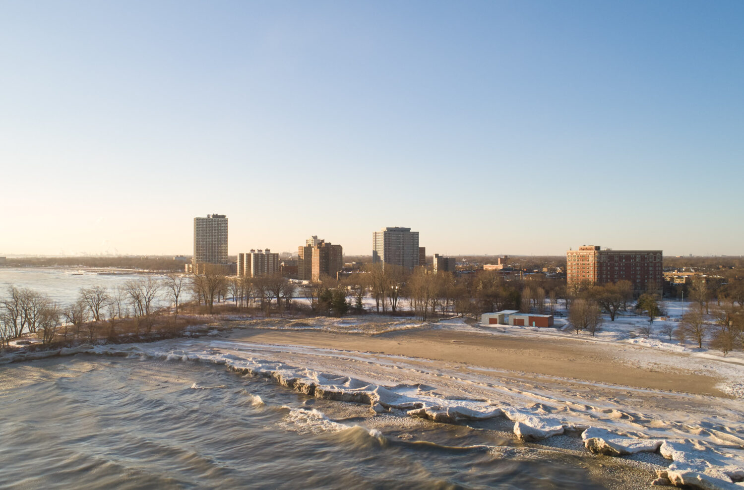 Aerial view of South Shore Beach House in winter, ice along the Lake Michigan shore and South Shore high-rises in low sun