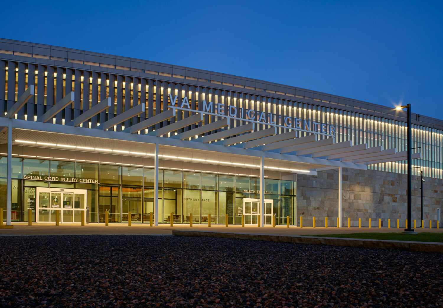 Main entrance at night beneath a long lit canopy, Rocky Mountain Regional VA Medical Center by SOM, Aurora, Colorado