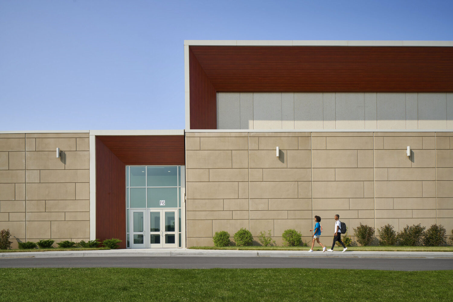 Low red and white facade with a glass entrance and young trees along the lawn at Rich Township High School